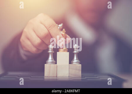 Business man holding golden re scacchi al vincitore posizione sul cubo di legno del gioco degli scacchi Foto Stock