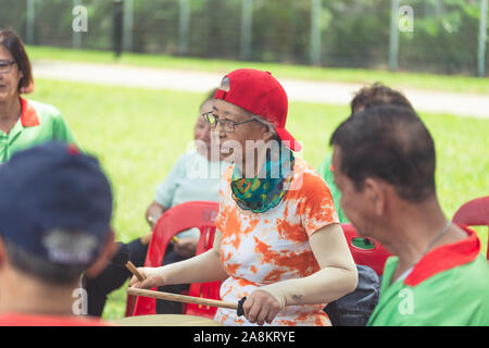 Un gruppo di anziani anziani pensionati attivi uomini asiatici donne suonare uno strumento musicale cantando allegramente godendosi la vita all'aperto Foto Stock