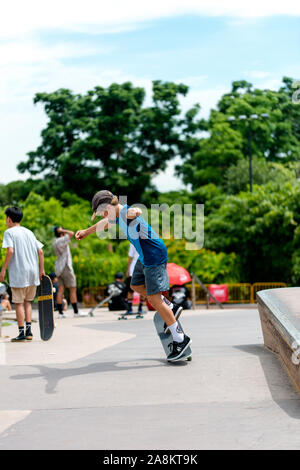 Giovane maschio boy skater che espongono la loro scheda competenze di pattinaggio all'aperto in skatepark Foto Stock