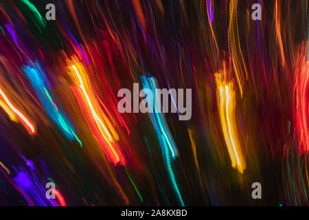 Sacco di variopinte sfocata e diagonale verticale strisce incandescente su sfondo scuro. Abstract sfondo al neon. Effetto fotografico con una lunga esposizione Foto Stock