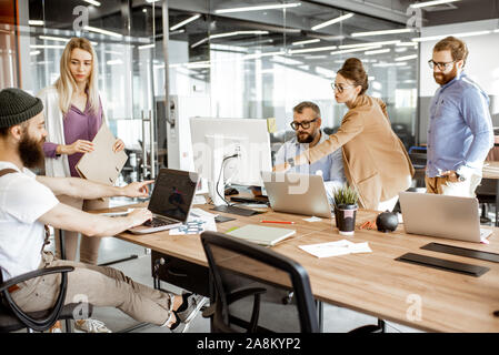 Gruppo di diversi colleghi lavorando sul computer in ufficio moderno o coworking space, parigamba barbuto come programmatore la scrittura di codice Foto Stock