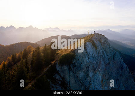 Vista aerea dell'uomo in piedi sulla cima di una montagna vicino a una croce. Vista dall'alto da flying drone. Natura Foto Stock