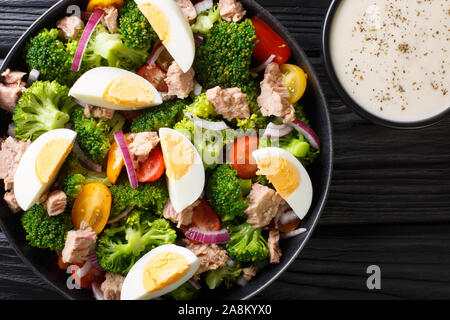 La prima colazione con insalata di tonno, broccoli, pomodori, cipolle e uova e dressing di yogurt closeup in una piastra sul tavolo. Parte superiore orizzontale vista da sopra Foto Stock