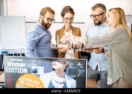 Gruppo di diverse persone creative avente una piccola discussione, lavorando come un web designer in un ufficio moderno o la coworking space Foto Stock