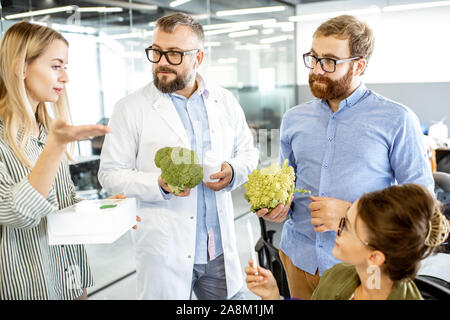 Gruppo di diverse persone che lavorano su un nuovo prodotto di eco o integratore dietetico in ufficio. Branding e sviluppo di nuovi alimenti alla moda di concetto Foto Stock