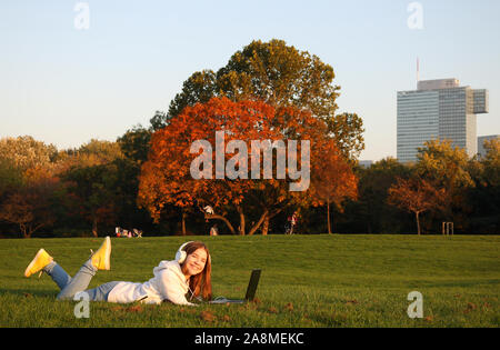 Felice ragazza adolescente si posa sul prato con un laptop in Donaupark Vienna Foto Stock