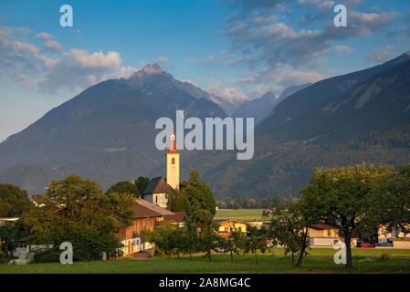 Chiesa parrocchiale di San Margarethen nella prima luce del mattino, dietro di essa sulle montagne del Karwendel, Buch in Tirolo Tirolo, Austria Foto Stock