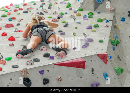 Scalatore durante il faticoso allenamento in corrispondenza di una parete di arrampicata indoor hall Foto Stock