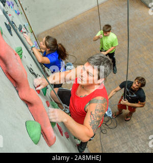 Scalatore durante il faticoso allenamento in corrispondenza di una parete di arrampicata indoor hall Foto Stock