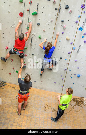 Scalatore durante il faticoso allenamento in corrispondenza di una parete di arrampicata indoor hall Foto Stock