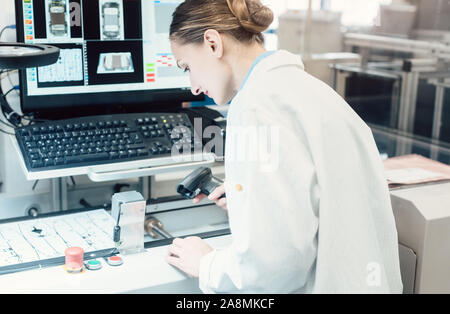 Lavoratore in Electronics fabbrica codice di scansione per ispezione ottica Foto Stock