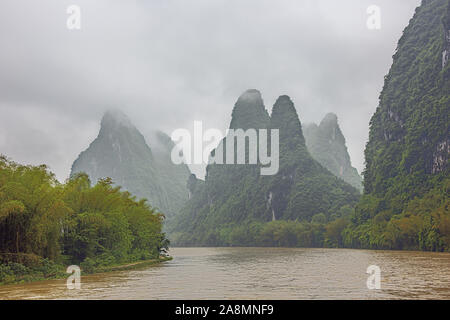 Ripide colline al confine con il Fiume Li rivolta verso le nuvole in prossimità di Yangshuo vicino a Guilin Foto Stock