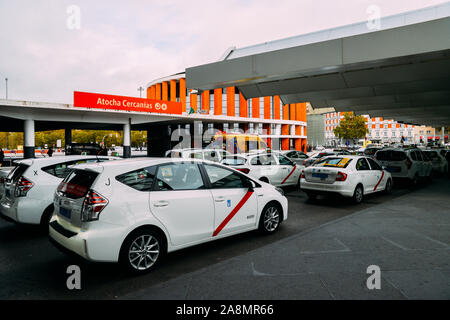 Madrid, Spagna - Novembre 9, 2019: fila di taxi bianco di fronte alla stazione ferroviaria di Atocha di Madrid in Spagna in attesa per i passeggeri Foto Stock