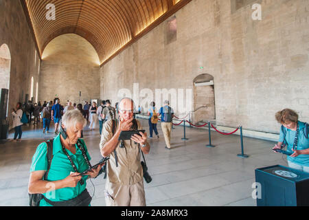 Avignone, PROVENZA / Francia - 27 Settembre 2018: grey-haired pensionati per cuffie con audio guide visita gli interni del Palazzo Papale Foto Stock