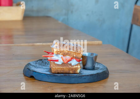 Waffle Strawerry panna fresca nella piastra nera su un tavolo di legno. Foto Stock