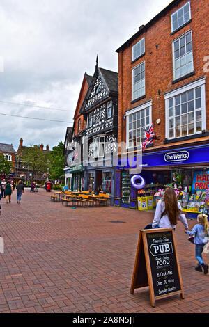 Una vista di una parte di High Street nel centro di Nantwich, guardando verso la Piazza della Città e Memoriale di guerra. Madre e figlia giovane passato a piedi negozi. Foto Stock
