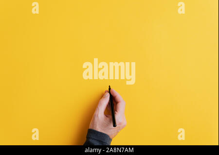 Maschio di scrittura a mano su di uno sbozzato superficie gialla con pennarello nero. Con spazio copia pronta per il tuo testo, messaggio o promozione. Foto Stock