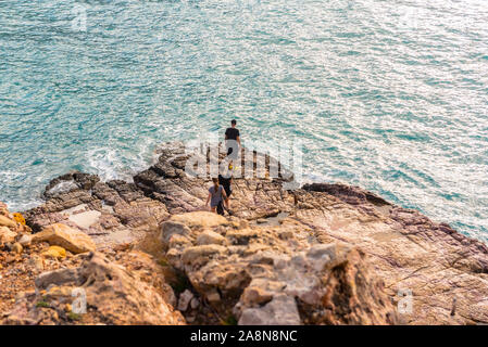Cala Salada e Saladeta, Ibiza, Spagna : 2019 novembre 04: 3 youngs soggiorno nella roccia in inverno a Cala Salada in San Antonio Abad a Isole Baleari Foto Stock