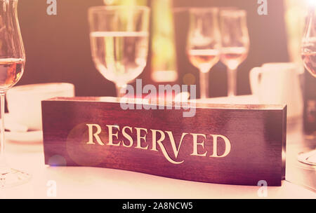 Riservato in legno piastra su un ristorante convenzionato tabella, tonica immagine Foto Stock