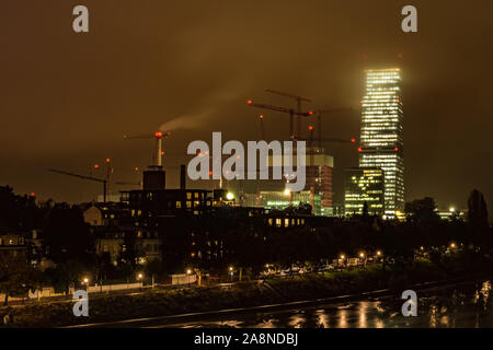 Drammatico paesaggio di un grande cantiere in una piovosa e notte di nebbia a Basilea, con la torre di Roche, Svizzera. Foto Stock