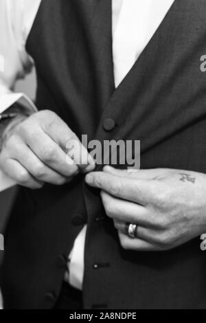 Un uomo sposo mettendo sul suo bretelle, i rigonfiamenti di loro alla sua pantaloni sul suo giorno di nozze. Abito formale, stilista e elegante, di fissaggio Foto Stock