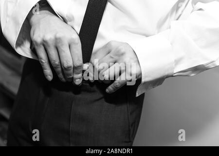 Un uomo sposo mettendo sul suo bretelle, i rigonfiamenti di loro alla sua pantaloni sul suo giorno di nozze. Abito formale, stilista e elegante, di fissaggio Foto Stock