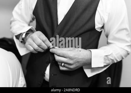 Un uomo sposo mettendo sul suo bretelle, i rigonfiamenti di loro alla sua pantaloni sul suo giorno di nozze. Abito formale, stilista e elegante, di fissaggio Foto Stock