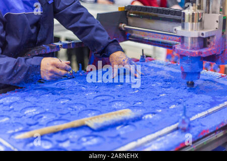 Macchina fresatrice durante il lavoro con blu di materiale plastico in corrispondenza di technology trade show Foto Stock