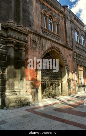 Una stretta casa a due piani di tufo rosso con finestre ovali e un ingresso ad arco coperto con il nero cancelli in ferro battuto Foto Stock