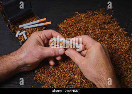 L'uomo fa una sigaretta, un rotolo di tabacco in carta tissue Foto Stock