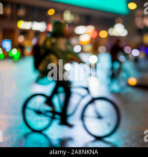 Abstract irriconoscibile silhouette uomo, equitazione biciclette, night city, illuminazione bokeh, motion blur. Uno stile di vita sano, attività di svago di concetto. Foto Stock