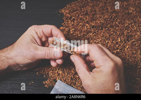 L'uomo fa una sigaretta, un rotolo di tabacco in carta tissue Foto Stock