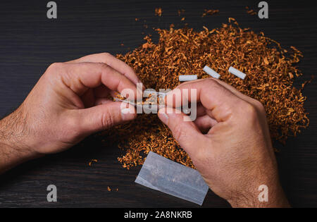 L'uomo fa una sigaretta, un rotolo di tabacco in carta tissue Foto Stock