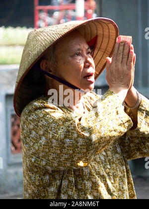 Donna anziana pregare presso un santuario. Foto Stock