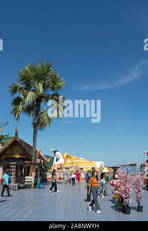 Nella parte anteriore di un Buddha reclinato scultura, visitatori presso la collina del Wat Phra That Doi kham, o tempio d'oro, vicino a Chiang Mai, Thailandia del Nord Foto Stock