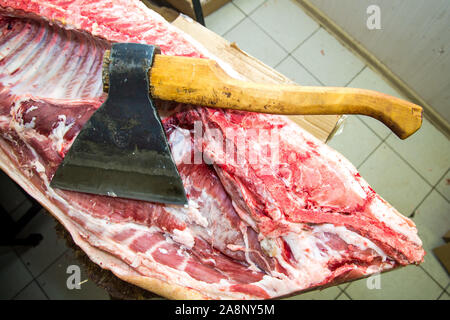 Grande ax per tritare la carne, di carcassa. Close up. Grande pezzo di carne. Professione di macellaio Foto Stock