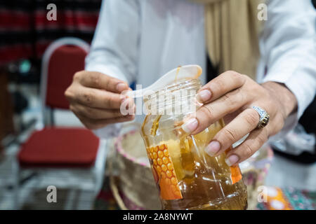 Un uomo è di dare un piccolo cucchiaio di la deluxe di alta qualità miele yemenita Foto Stock