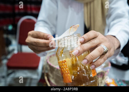 Un uomo è di dare un piccolo cucchiaio di la deluxe di alta qualità miele yemenita Foto Stock