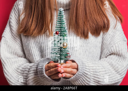 Donna in accogliente maglione decorativi di contenimento mini albero di Natale Foto Stock