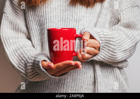 Immagine di una donna di mano che tiene un rosso tazza da caffè Foto Stock