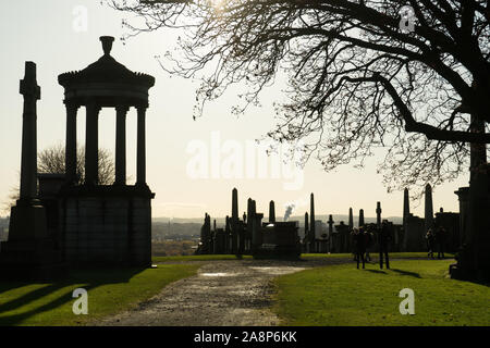 La soleggiata giornata autunnale del cimitero vittoriano necropoli in Regno Unito fotografato da lontano con la retroilluminazione di sun. Il cimitero di nero silhouette Foto Stock