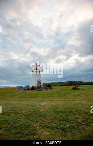Agosto 18, 2019 - Economia, Nova Scotia - il bianco e il rosso faro contro un cliffside in Rurale Nova Scotia su una sera Nuvoloso in estate Foto Stock