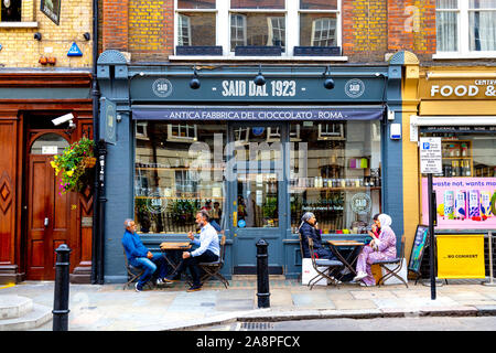 Persone di bere al di fuori di detto dal 1923 il negozio di cioccolato e caffè di Soho, London, Regno Unito Foto Stock