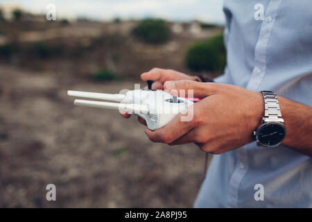 Drone telecomando. L'uomo azienda copter controller con lo smartphone. Antenna di riprese video Foto Stock