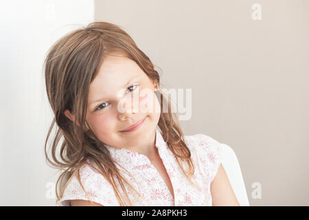 Sorridente poco bionda ragazza caucasica, close-up volto ritratto oltre il muro grigio sfondo Foto Stock