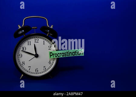 La procrastinazione scrivere sul foglietto adesivo isolato sfondo blu. Concetto di ritardo Foto Stock