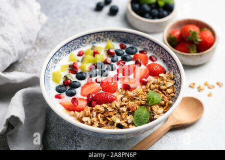 Tazza colazione con yogurt, muesli, frutta e frutti di bosco. Mirtillo, i semi di melograno, kiwi, fragola e crunchy granola di avena. Cibo sano Foto Stock