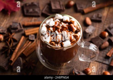 La tazza di cioccolata calda con marshmallows e cannella su un marrone tavolo in legno. Comfort food, bevanda di Natale Foto Stock