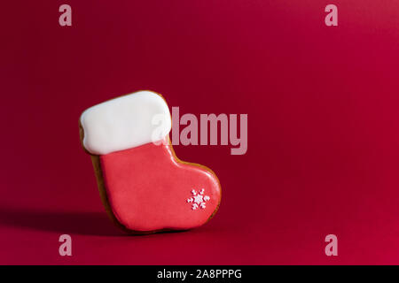 Gingerbread cookie di Santa il calzino su sfondo rosso. Tradizionale cibo di Natale. Natale e Anno Nuovo Concetto di vacanza. Copyspace. Foto Stock