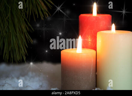 Candele accese con pini nella neve su sfondo nero. Vacanza e tema natale Foto Stock